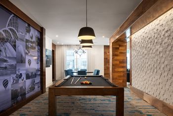 A room with a pool table and a large picture on the wall